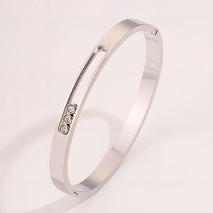 Detail of silver titanium steel bangle featuring three sliding diamonds in a grooved track