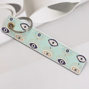 Detail of the faux leather keychain featuring a textured evil eye pattern and gold ring