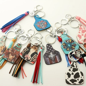 Close-up of Western cow tag keychains with leather fringe, sunflower and bull skull patterns