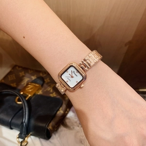 Close-up of rose gold square watch with pearl face and diamond-accented indices on wrist