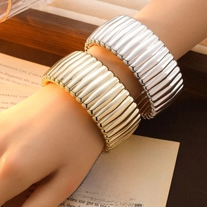 Detailed view of gold and silver textured metal cuff bracelets with pleated design