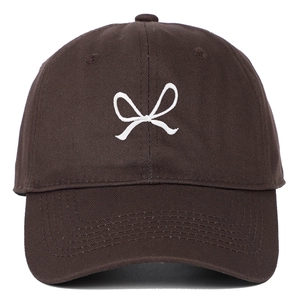 Close-up of a dark brown baseball cap featuring a white embroidered bow design