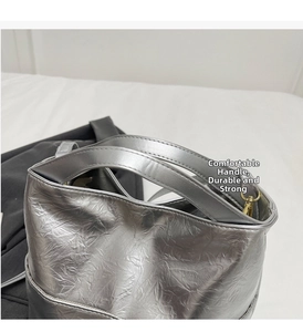 Detail of silver textured bucket bag featuring dual reinforced handles and metallic hardware
