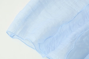 Macro shot of light blue semi-transparent fabric with delicate ruffled lettuce edge detail
