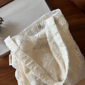 Detail of off-white lace tote bag with leaf embroidery and silver metallic buckle