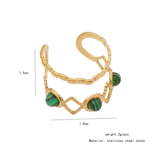 Macro view of gold stainless steel ear cuff with green stones and chain link detail