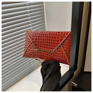 Detail of red crocodile texture handbag with gold metal trim and snap closure