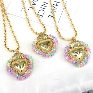 Detailed view of heart pendants with colorful bead borders and golden bead chains on white