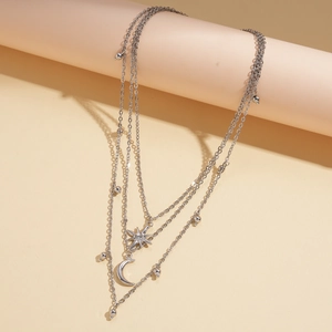 Macro detail of multi-layered silver necklace with star and crescent moon pendants