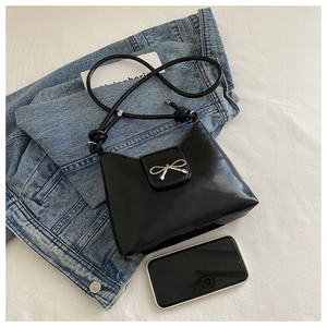 Detailed shot of a black leather handbag featuring a stylish silver bow metal ornament