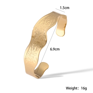 Detailed view of wave textured gold cuff bracelet with 1.5cm width and 6.9cm diameter