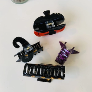 Detail view of Halloween hair clips featuring pumpkin, witch hat and bat wing designs