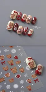 Detailed view of 3D bear nail art stickers with red bows and strawberry patterns