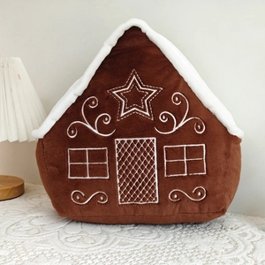 Detailed close-up of a gingerbread house plush pillow with festive embroidery on soft fabric