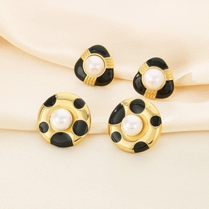 French vintage gold earrings set with pearls and black enamel details on beige silk