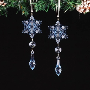 Close-up of blue crystal snowflake ornaments with teardrop pendants on pine branches