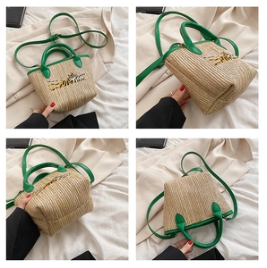 Detail view of beige straw basket bag with green leather straps and tiger embroidery