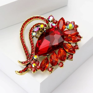 Macro detail of red pear-cut crystal brooch with golden base on white display stand