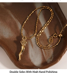Detailed macro of gold cornicello necklace with adjustable slider on ceramic plate