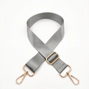 Detail of adjustable grey nylon bag strap with polished gold metal buckles and hooks