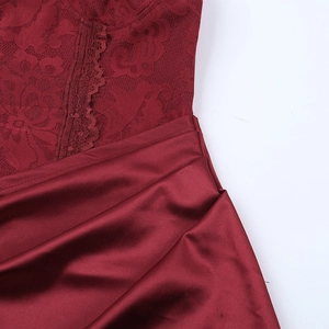 Detail of burgundy evening gown featuring intricate lace stitching and silky satin fabric
