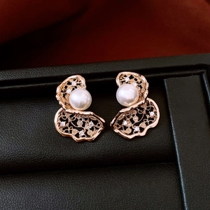 Macro detail of 18K gold-plated flower earring with white pearl and sparkling crystals