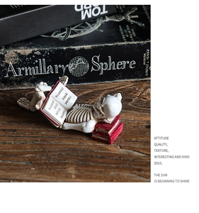 Detail of creative skeleton figurine reading a red book on a dark wood grain desk