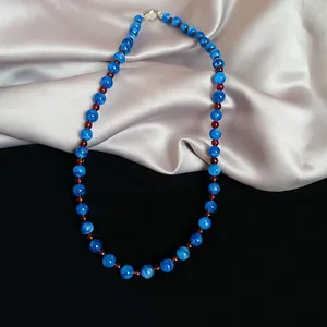 Elegant beaded necklace featuring blue translucent stones and red accents on silk background