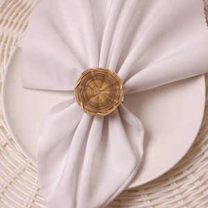Close-up of a natural rattan round napkin ring with a white cloth on a plate