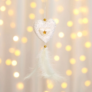 Detailed close-up of a knitted heart Christmas ornament with stars and soft white feathers