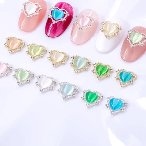 Détail de bijoux d'ongles en forme de cœur œil-de-chat avec bordure en strass