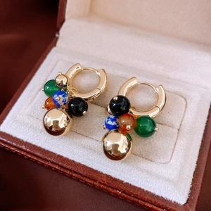 Gros plan détaillé de boucles d'oreilles créoles dorées avec perles colorées en boîte