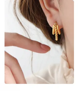 Detail of minimalist 18K gold plated twisted rope C-shape hoop earrings on a model