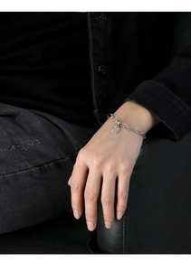 Detailed macro view of silver chain bracelet with round coin pendant on a male model