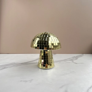 Macro detail of a golden mushroom disco ball with reflective mirror glass tiles on marble