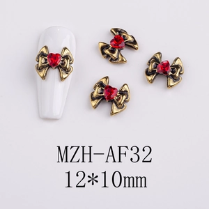 Detailed view of vintage gold bow nail charms with red heart rhinestone on white tip