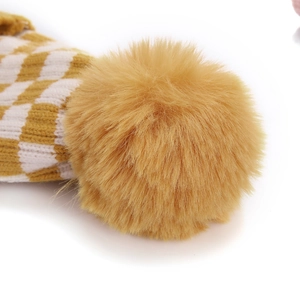 Détail du motif tricoté en damier jaune avec un pompon en fausse fourrure moelleuse