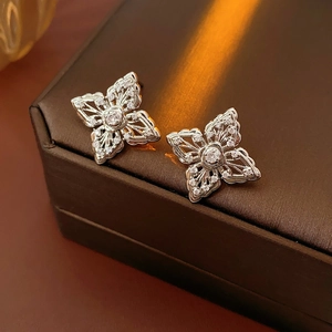 Macro shot of silver hollow flower earrings featuring zircon micro-paving and center stone
