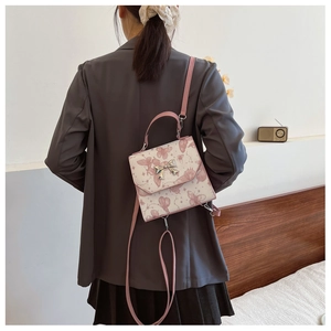 Rear view of a model wearing a pink and white butterfly print versatile backpack and shoulder bag