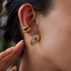 Macro shot of gold ear cuff and two-tone star earrings on model ear for detail