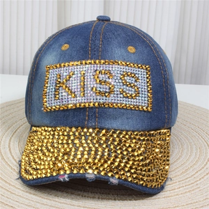 Detail of blue denim baseball cap featuring KISS letters and gold stud embellishments