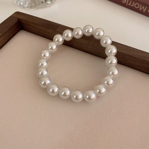 Close-up of elegant white pearl stretch bracelet on a vintage beige textured background