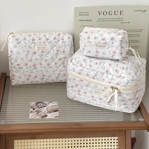 Detailed set of three quilted cotton cosmetic bags with pink floral and bow patterns