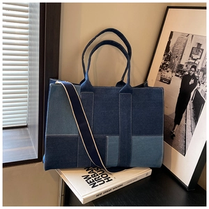 Close-up of patchwork denim tote bag with textured blue panels and wide shoulder strap