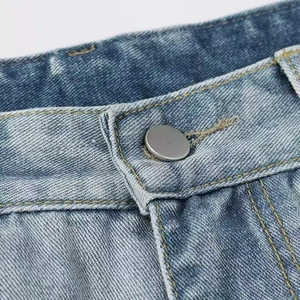 Gros plan détaillé du bouton en métal et des coutures sur un jean en denim bleu