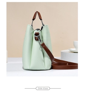 Close-up of mint green pebble leather tote bag side view with brown strap and metal D-ring