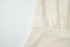 Macro shot of ivory lace patchwork fabric with intricate floral patterns and smooth texture