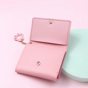 Detail of pink tri-fold wallet with leather texture and cute cat paw metal chain charm