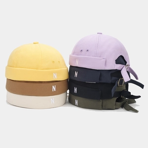 Detailed view of N embroidered docker hats in various colors with adjustable metal buckle