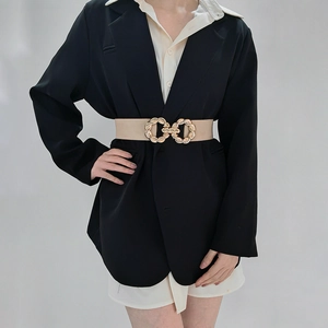 Detail of beige elastic waist belt with interlocking gold buckle on coat